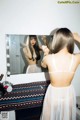 A woman standing in front of a mirror brushing her hair.