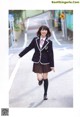 A woman in a school uniform is walking down the street.