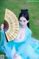 A woman in a blue dress holding a fan.