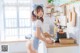 A woman in a blue and white dress standing in a kitchen.