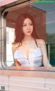 A woman in a white dress is looking out the window of a train.