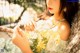 A woman sitting on a bench holding a bunch of flowers.