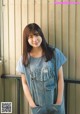 A young woman standing in front of a metal wall.