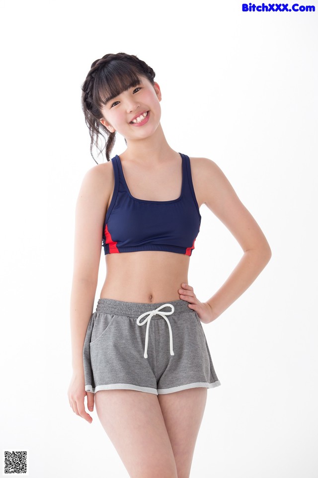 A woman in a sports bra top and shorts posing for a picture.