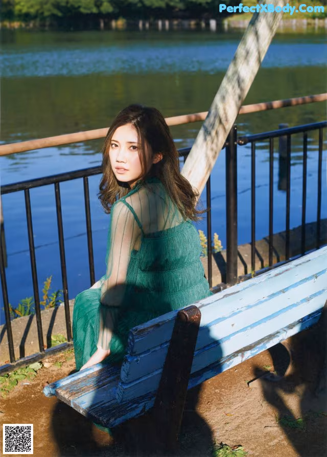 A woman in a green dress sitting on a bench.