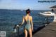 A woman in a bathing suit standing on a dock by the water.