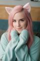 A woman with pink hair wearing a cat ears headband.