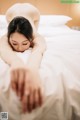 A naked woman laying on a bed with her hands on the bed.