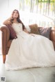 A woman in a wedding dress sitting on a couch.