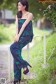 A woman in a blue and green jumpsuit sitting on a railing.