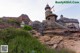 A castle on top of a rocky hillside next to a forest.