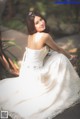 A woman in a wedding dress sitting on a wooden bench.