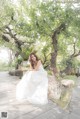 A woman in a wedding dress sitting on a rock.