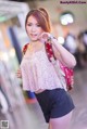 A woman in shorts and a pink top is posing for a picture.