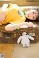 A woman laying on top of a suitcase next to a stuffed animal.