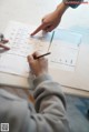 A person pointing at a piece of paper on a table.