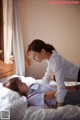 A woman in a white shirt and a woman laying on a bed.