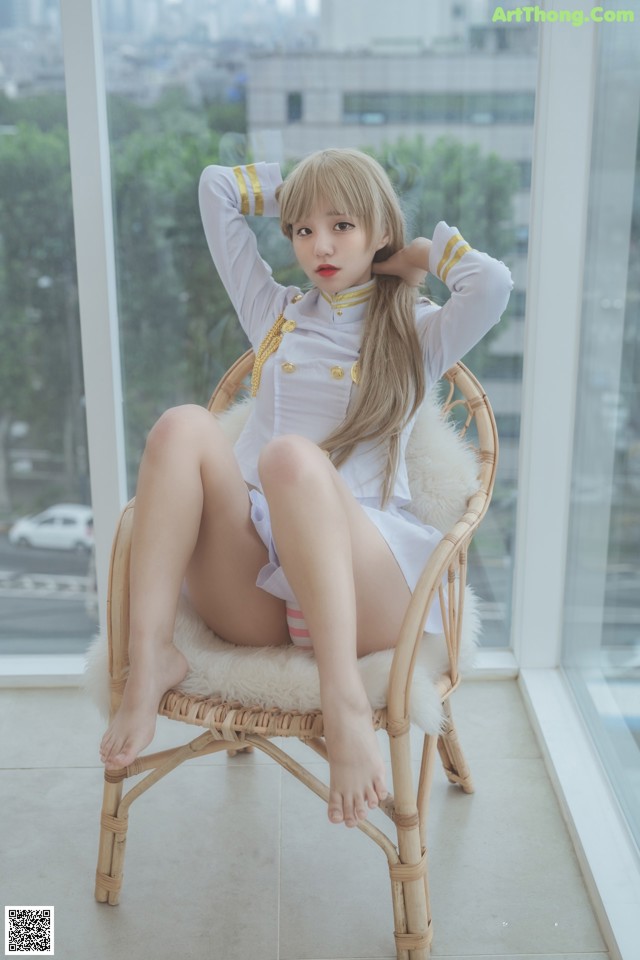A woman sitting on a wicker chair in front of a window.