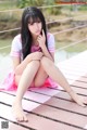 A woman sitting on a wooden bridge with her legs crossed.