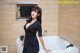 A woman in a black dress standing in a bathtub.