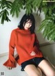 A woman in a red sweater sitting on the floor.