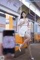 A woman in a white dress sitting on a subway train.