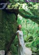 A woman in a white dress standing in front of a rock.